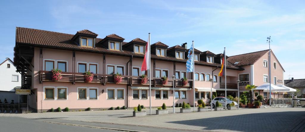 a large pink building with flags in front of it at Hotel Vierjahreszeiten in Breitengüßbach