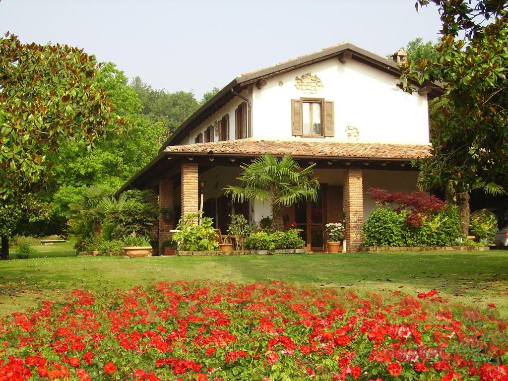 una casa con flores rojas delante de ella en B&B Soiano Del Lago, en Soiano del Lago