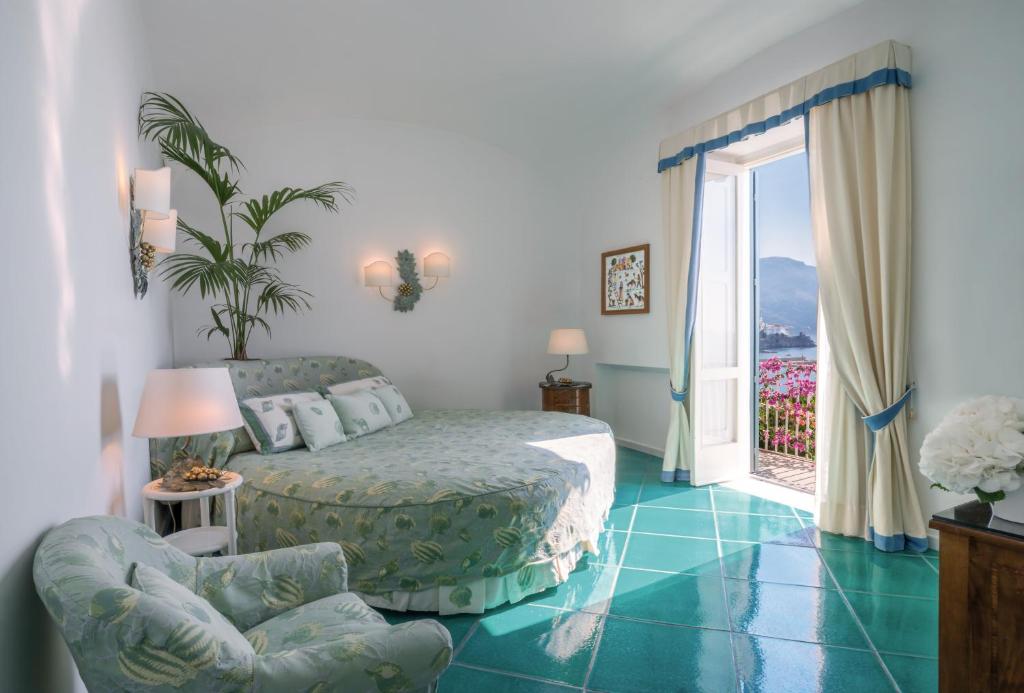 a bedroom with a bed and a chair and a window at Hotel Santa Caterina in Amalfi