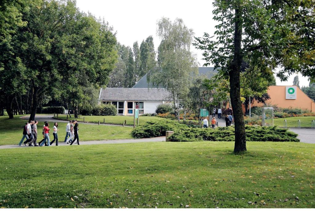 a group of people walking down a sidewalk in a park at Ethic Etapes Lac De Maine in Angers