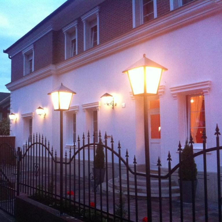 a white house with a fence and lights at Peron in Debrecen