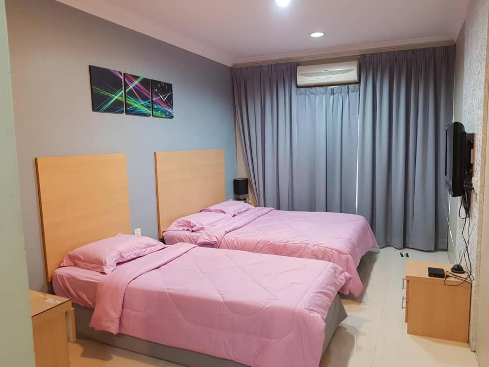 two beds in a bedroom with pink sheets at Hotel Budget Lestari in Kota Bharu