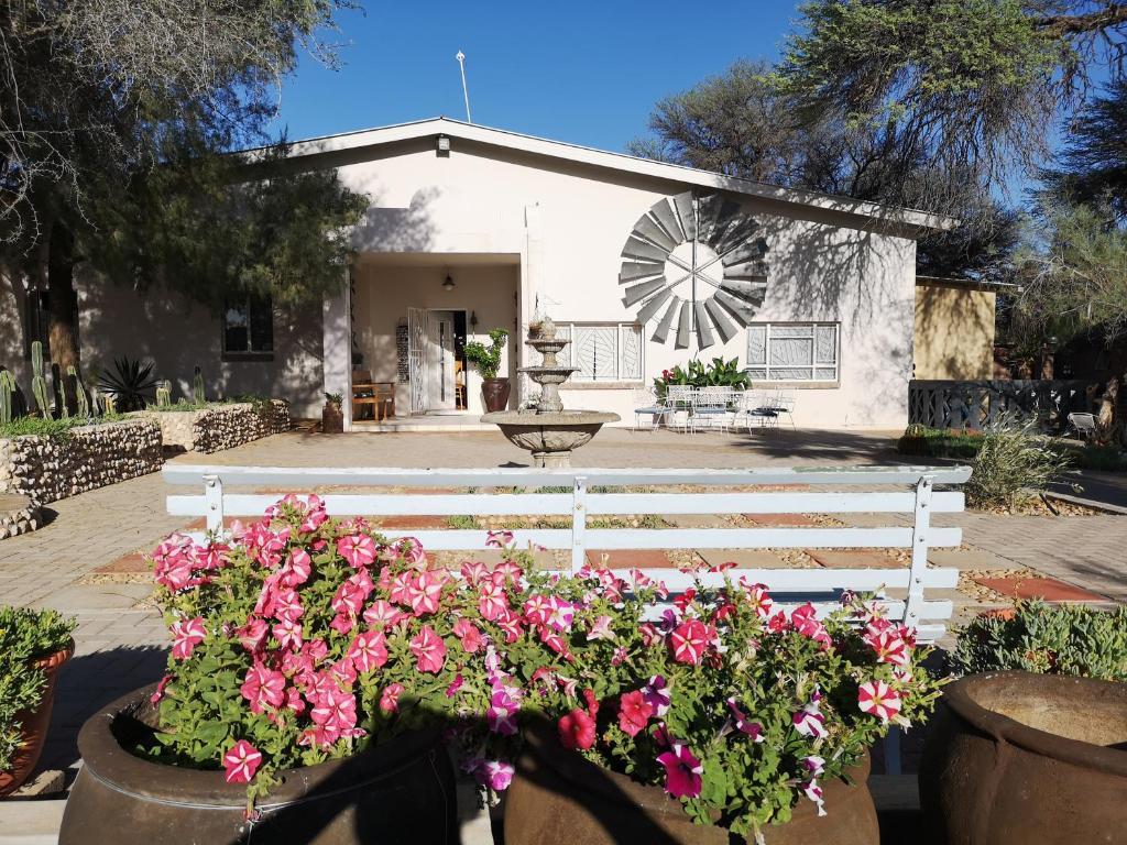 a white house with pink flowers and a windmill at Terra Rouge Guestfarm & Sonstraal Farmhouse in Koës