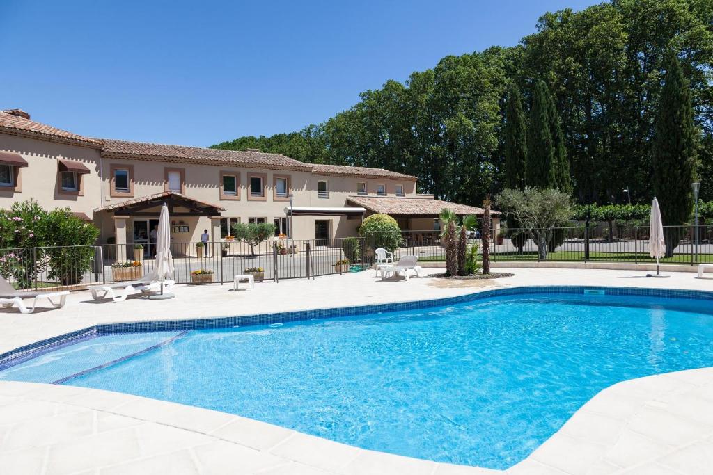 a swimming pool in front of a house at Logis Hôtel Le Mas De Jossyl in La Roque-dʼAnthéron