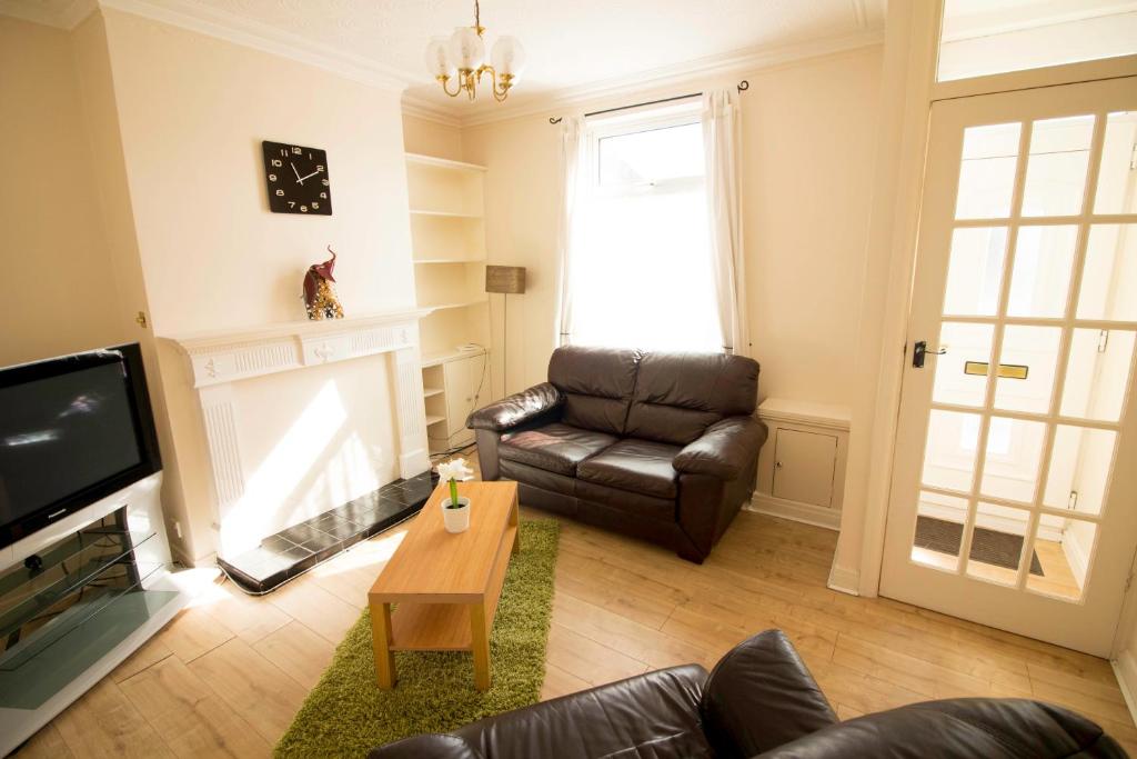 a living room with a leather couch and a television at Brook House in Selby