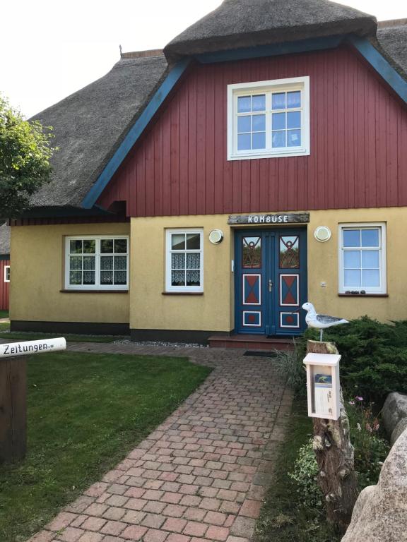 a red and yellow house with a blue door at "Steuermannskammer" by Ferienhaus Strandgut in Born