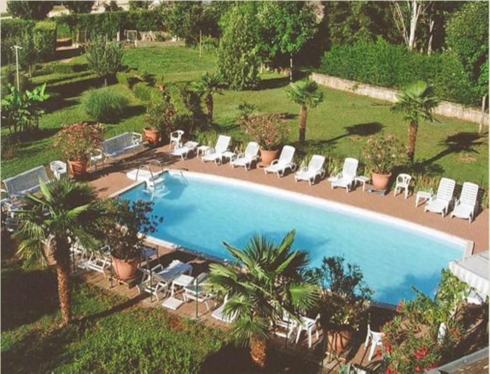 uma vista sobre uma piscina com cadeiras e palmeiras em Les Songes de Buxy em Buxy