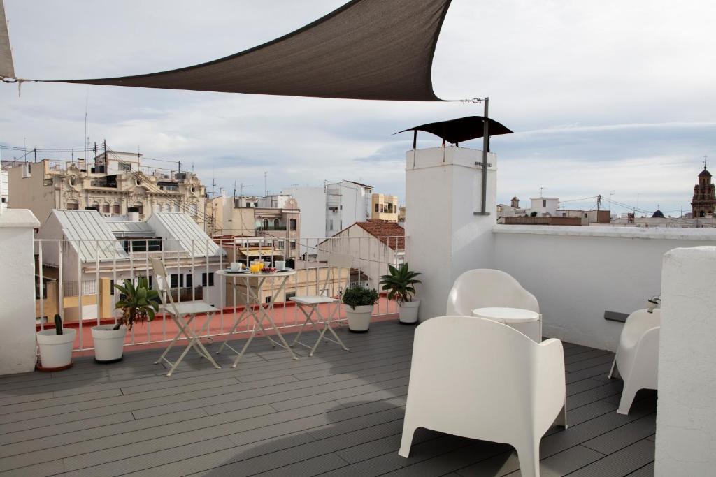 balcón con sillas blancas y vistas a la ciudad en FLORIT FLATS - Ático Oasis de Ruzafa, en Valencia