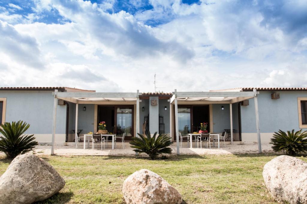 a house with chairs and tables in front of it at Punta del Cane in Fontane Bianche