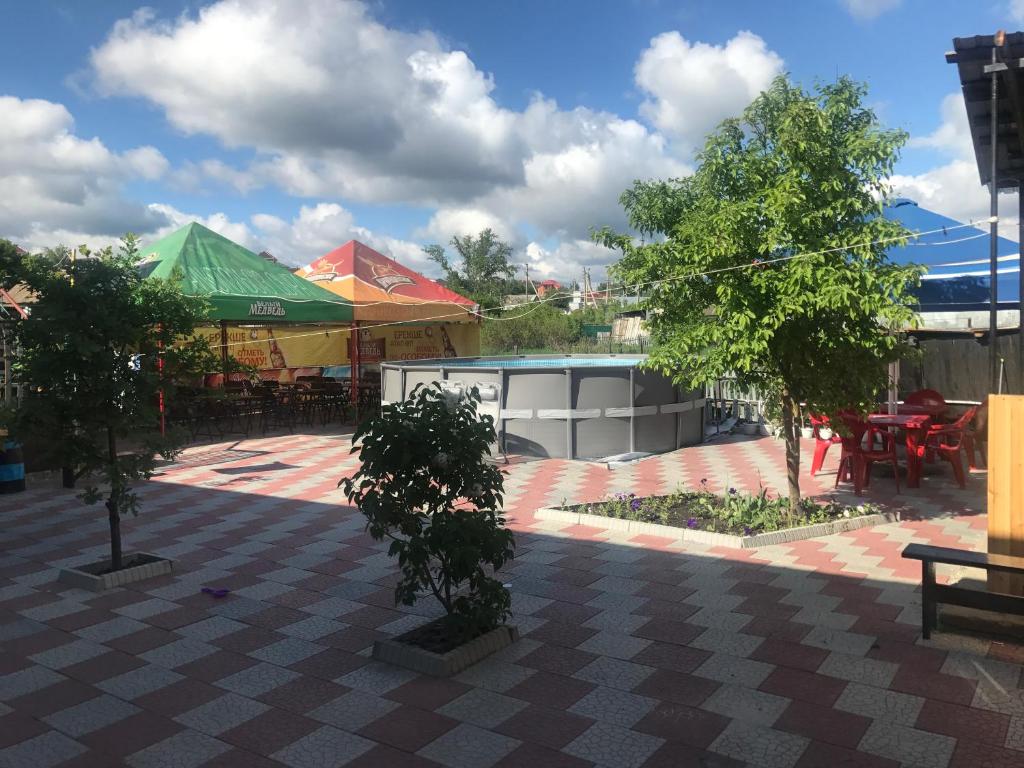 eine Terrasse mit Bäumen, Tischen und Sonnenschirmen in der Unterkunft Comfort Guest House in Borovoye