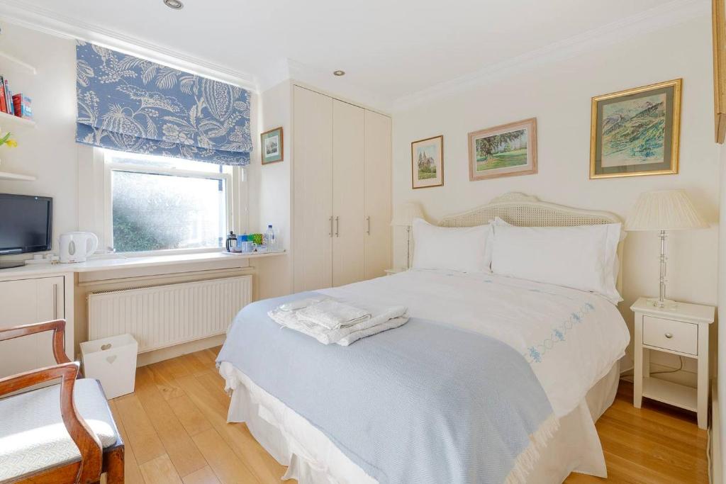 a white bedroom with a bed and a television at Fulham B&B in London