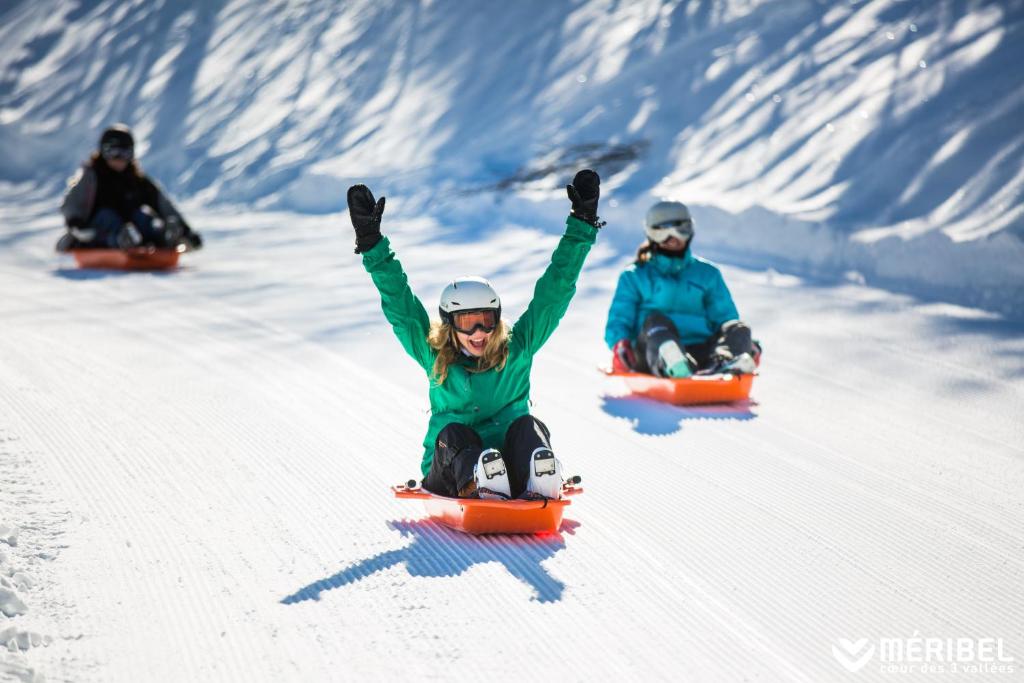 three people riding down a snow covered slope on snowboards at Le Kaïla in Méribel