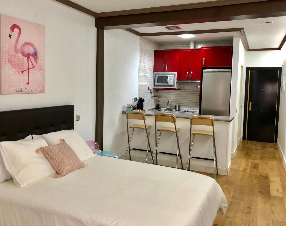 1 dormitorio con 1 cama y cocina con armarios rojos en CHUECA Apartamentos, en Madrid