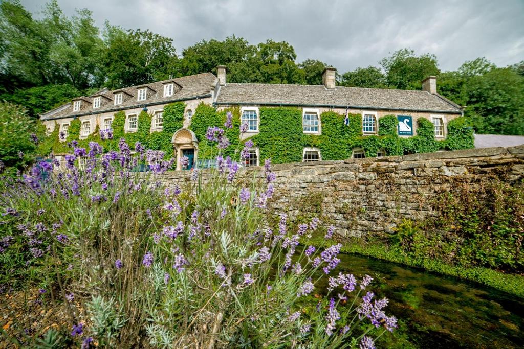 a stone house with flowers in front of it at The Swan Hotel in Bibury