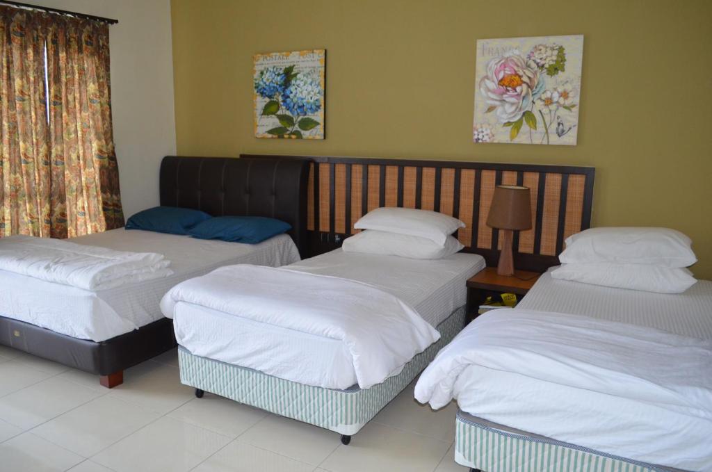 um quarto com três camas num quarto com uma janela em Gold Coast Morib Ain Studio em Kampong Tanjong Pechah