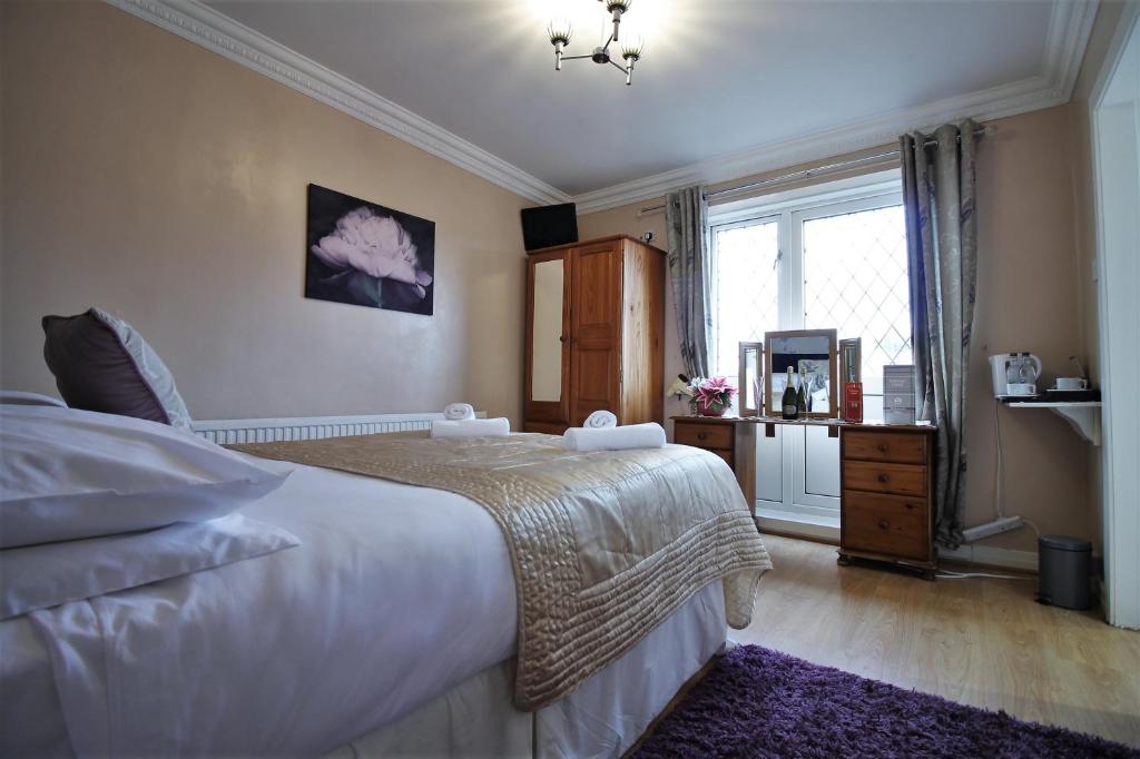 a bedroom with a large white bed and a window at Fairway Hotel in Bathgate