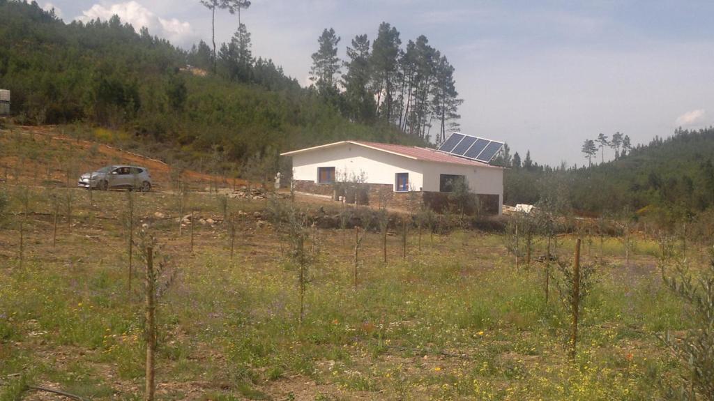 una casa in un campo con una macchina davanti di REFÚGIO DO RAPOSO/CASA DA RIBEIRA (AGROTURISMO) a Proença-a-Nova