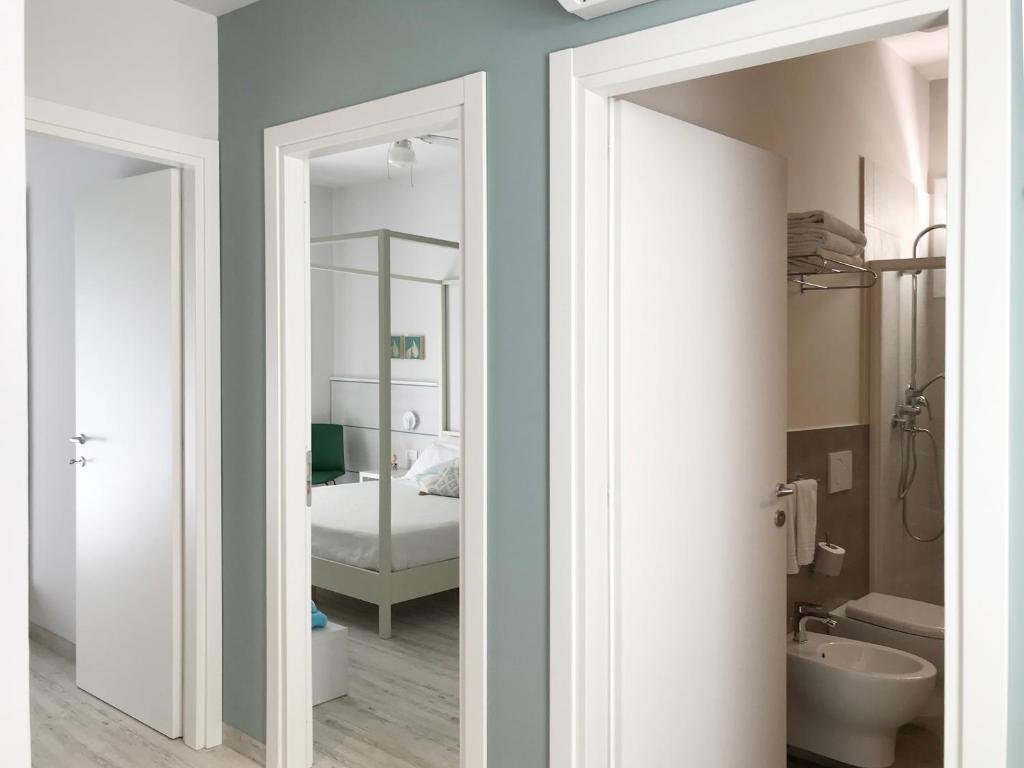 uma casa de banho com um espelho e um quarto com uma cama em Hotel Flora em Cattolica