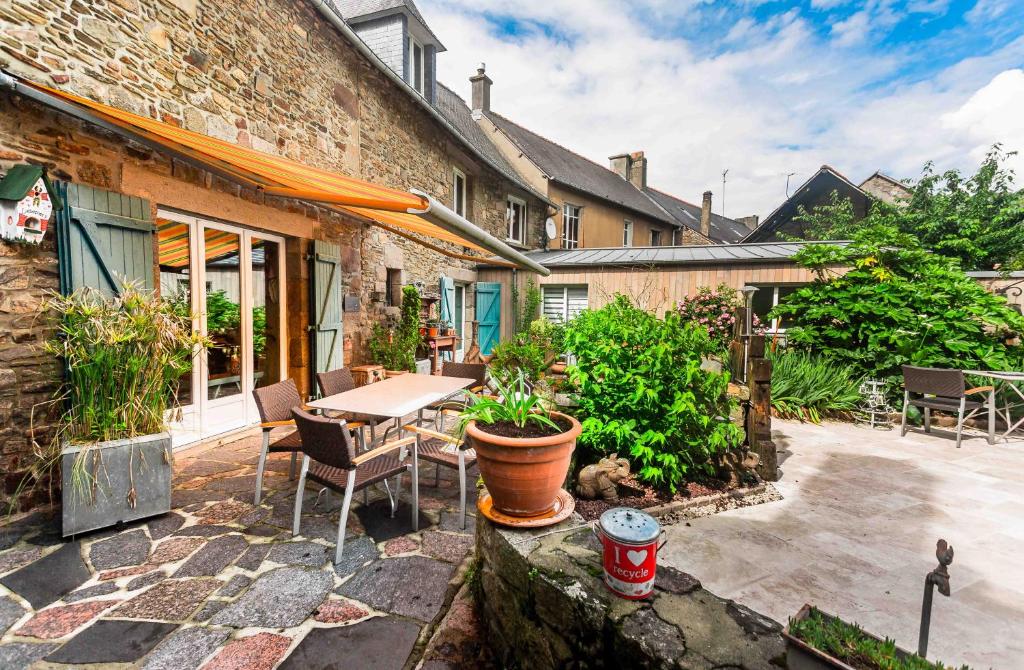 un patio con tavolo, sedie e un edificio di la maison d'idylle a Combourg