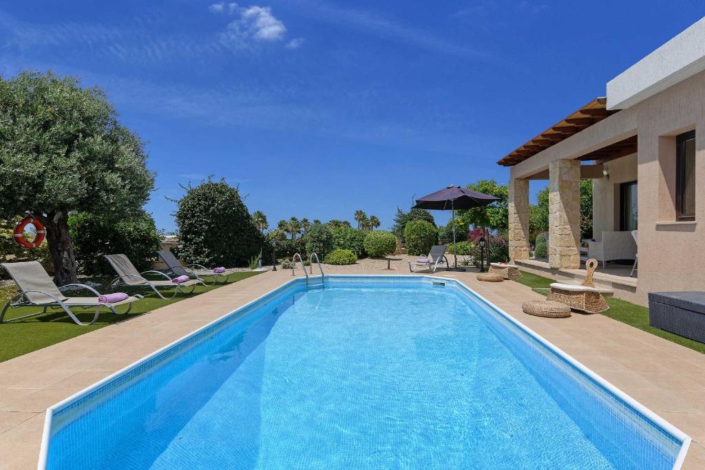 einen Pool in einem Garten mit Stühlen und einem Haus in der Unterkunft Villa Pashiana in Polis Chrysochous