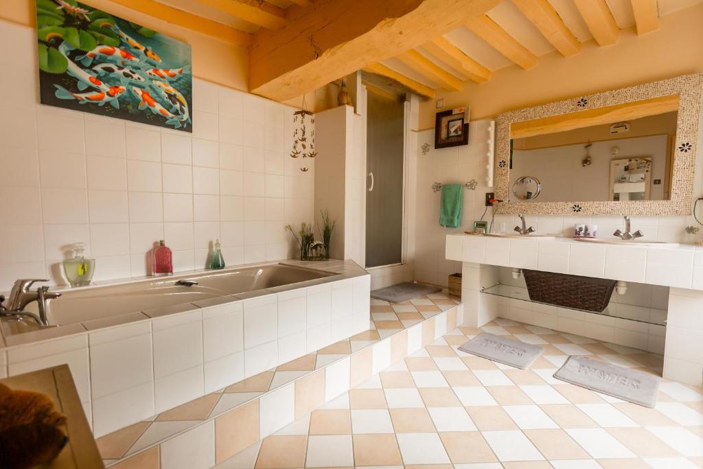 a bathroom with a tub and two sinks and a mirror at la maison d&#39;idylle in Combourg