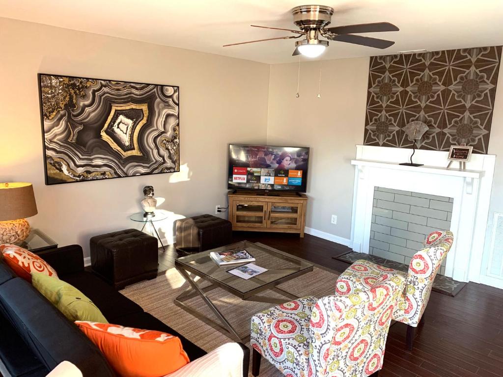 a living room with a couch and a tv at The Orange Door-Sleeps 10 in Louisville