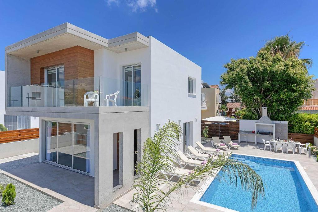 eine Villa mit einem Pool und einem Haus in der Unterkunft Villa Coral Bay in Peyia