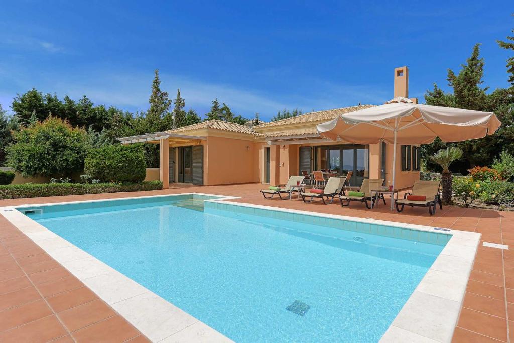 a swimming pool in front of a house with an umbrella at Villa Riaki in Kaligata