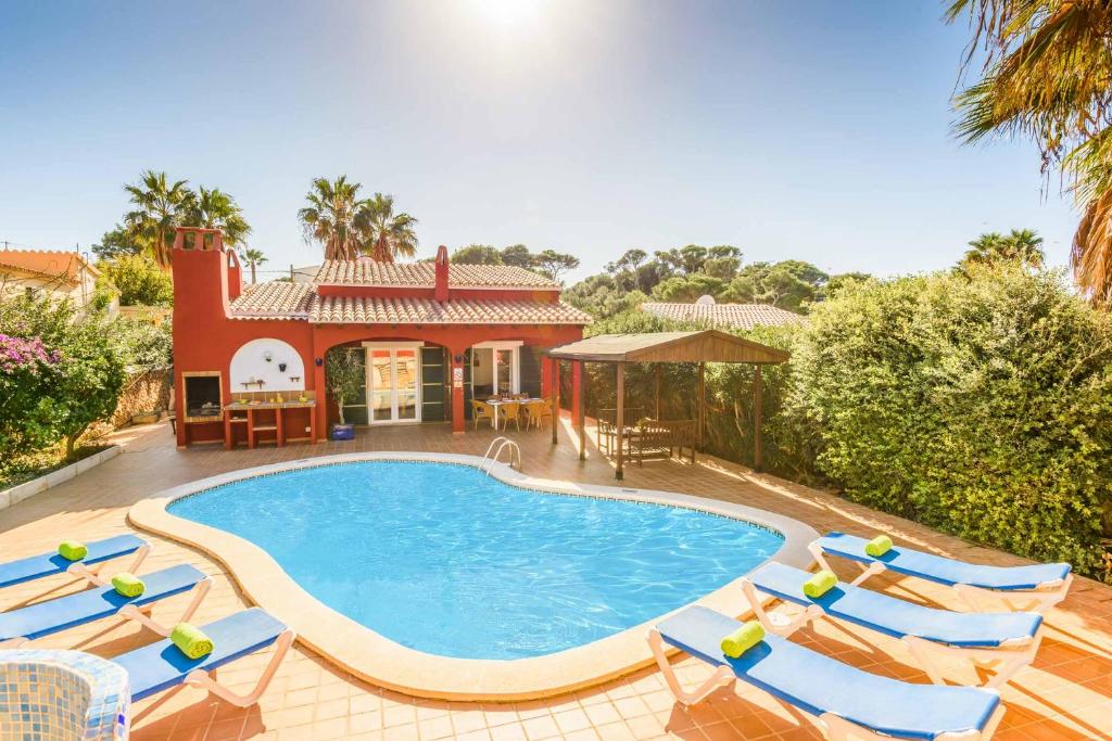 a swimming pool with chairs and a house at Villa Paula in Cala'n Porter