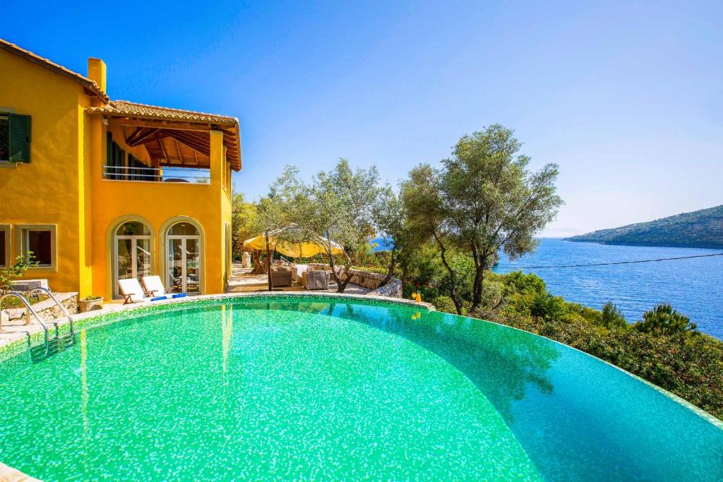 a swimming pool in front of a house with a view of the water at Villa Elpida in Sivota