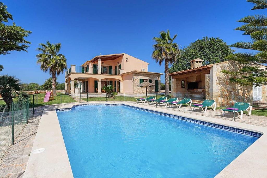 a house with a swimming pool in front of a house at Villa Deu Quarterades in Santanyi