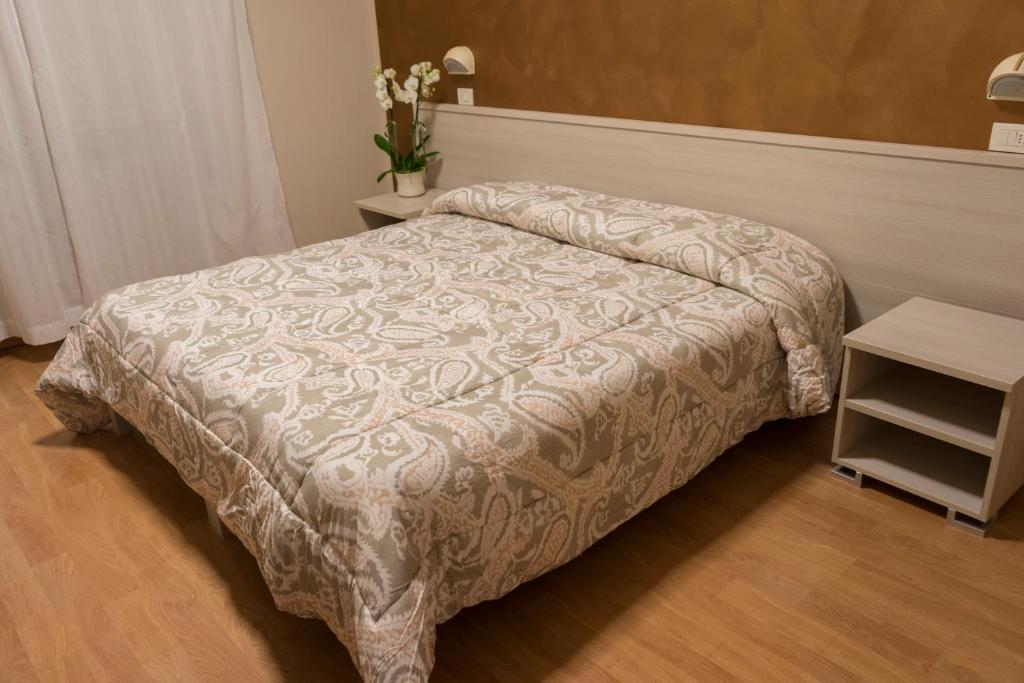 a bed in a bedroom with a table and a bedspread at Hotel Cecco in Arezzo