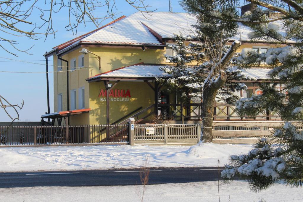 una casa amarilla con una cerca en la nieve en Bar Malwa, en Aleksandrów Łódzki