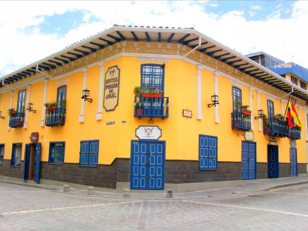 a yellow building with windows and balconies on a street at Hotel Posada del Angel in Cuenca