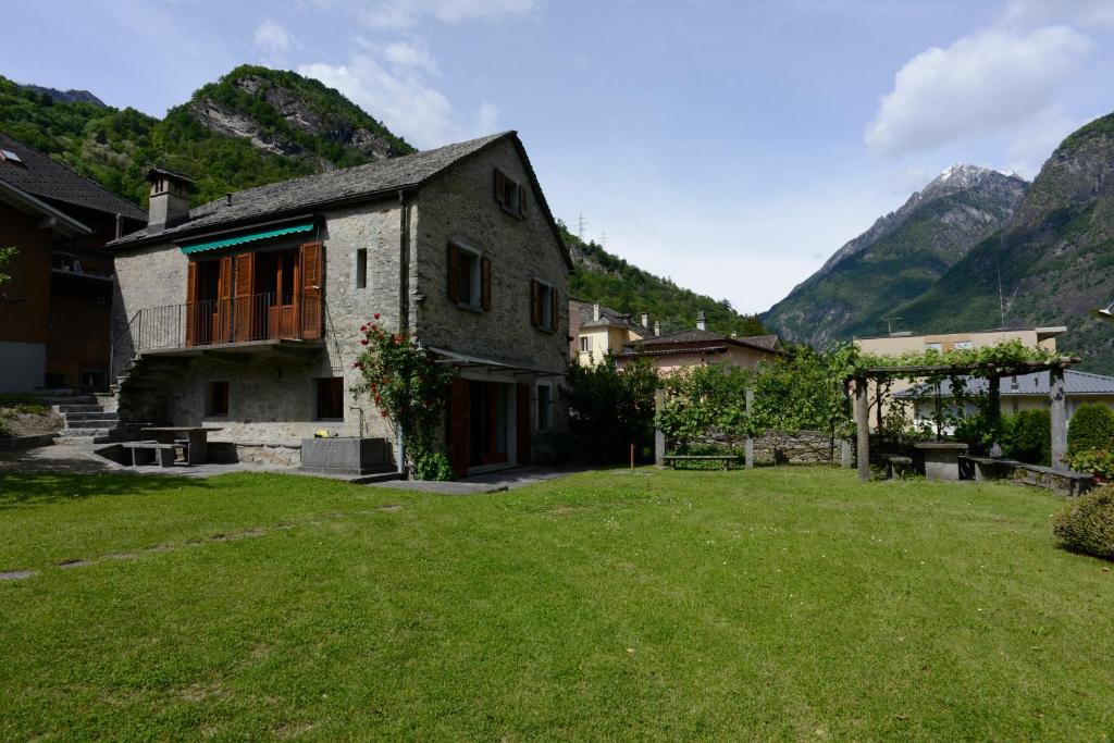 a house with a grass yard in front of mountains at Bed and Breakfast da Käthy Agriturismo in Grono