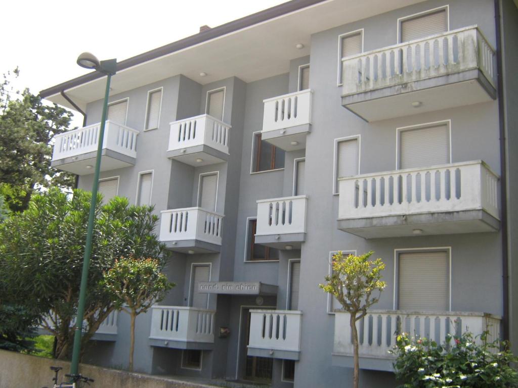 an apartment building with white balconies and trees at Condominio Rio Chico in Lignano Sabbiadoro