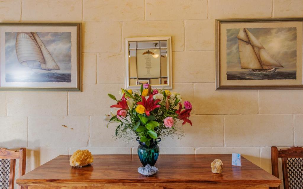 a vase of flowers on a table with two pictures at Ghajn Damma in Xagħra