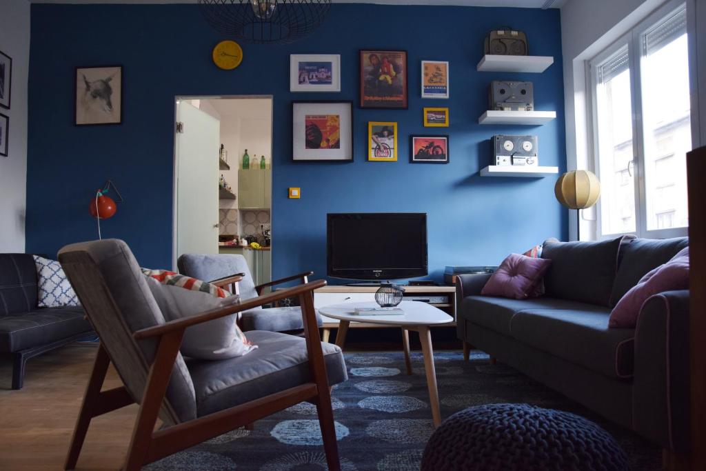 a blue living room with a couch and a tv at Bleak House - Bauhaus home in greener Budapest in Budapest