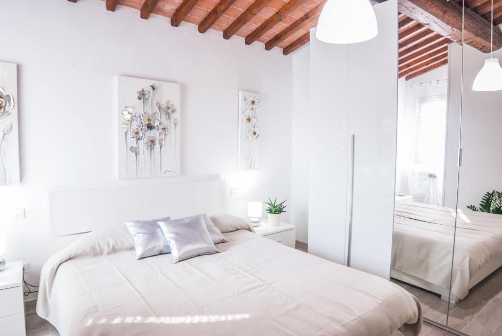 een witte slaapkamer met een bed en een spiegel bij Cascine Home Holidays in Florence