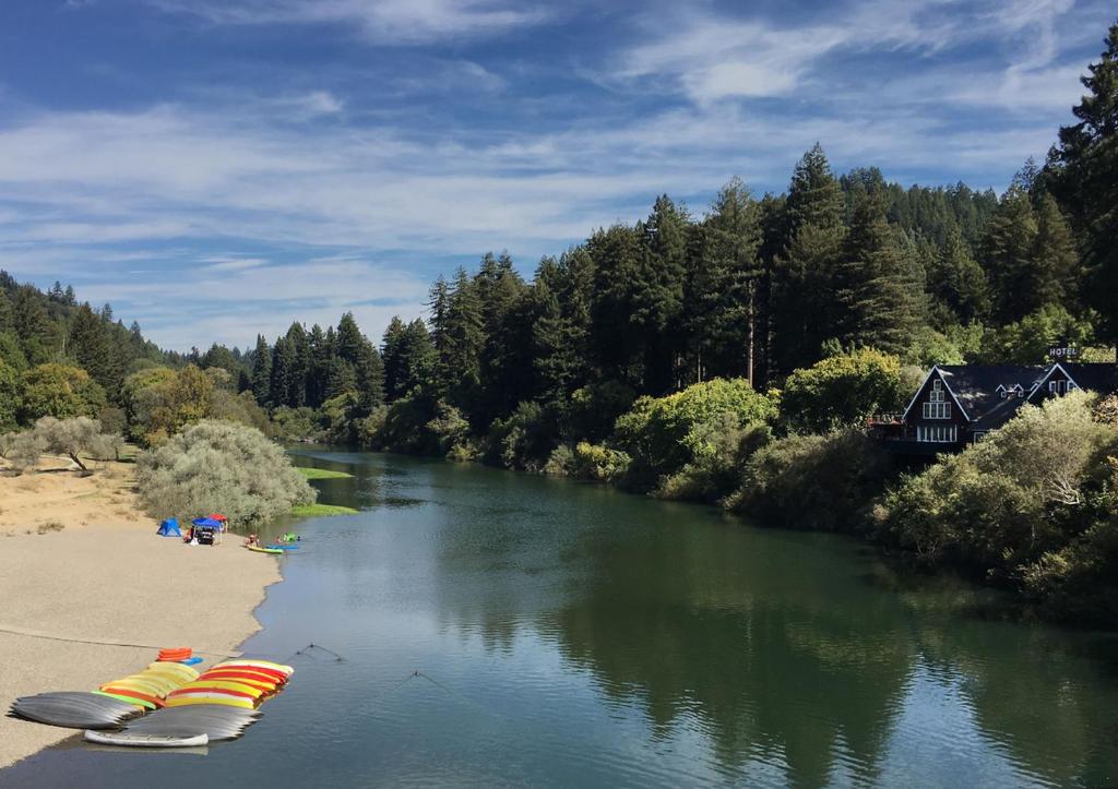 a river with a row of umbrellas on the shore at Inn on the Russian River in Monte Rio