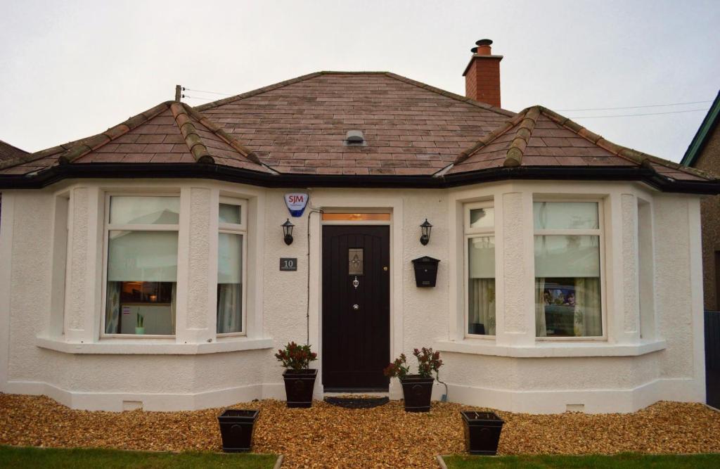 una casa bianca con porta nera e finestre di The Captains Cottage, Cushendall a Cushendall