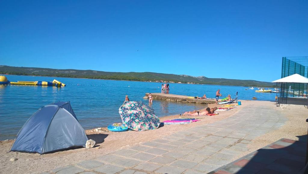 grupa ludzi na plaży z namiotem w obiekcie Apartament Jukić w mieście Sveti Filip i Jakov