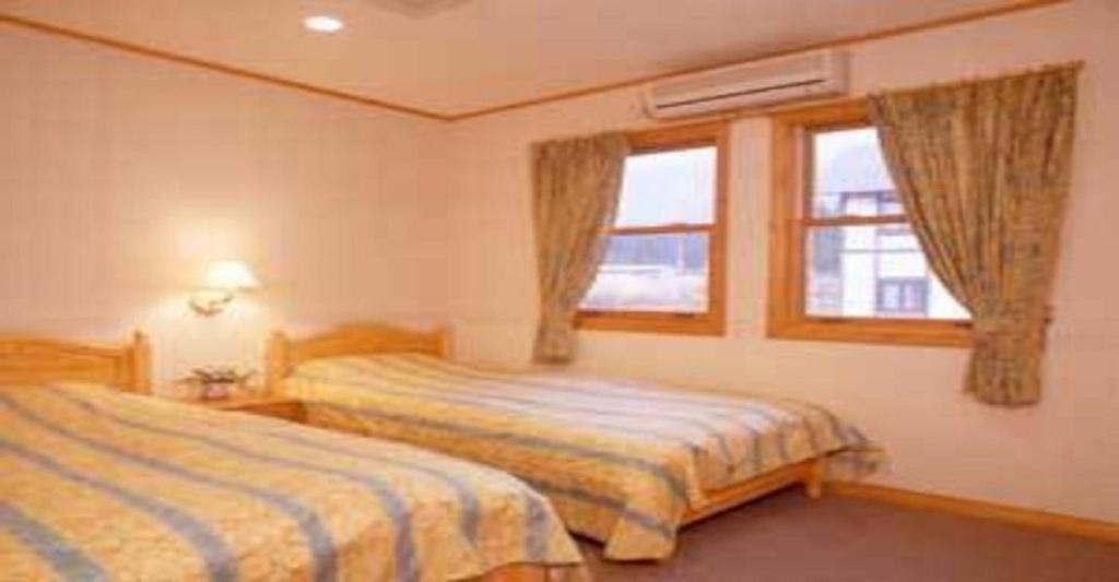 a bedroom with two beds and a window at Pension Come Western style room with bath and toilet - Vacation STAY 14966 in Minami Uonuma