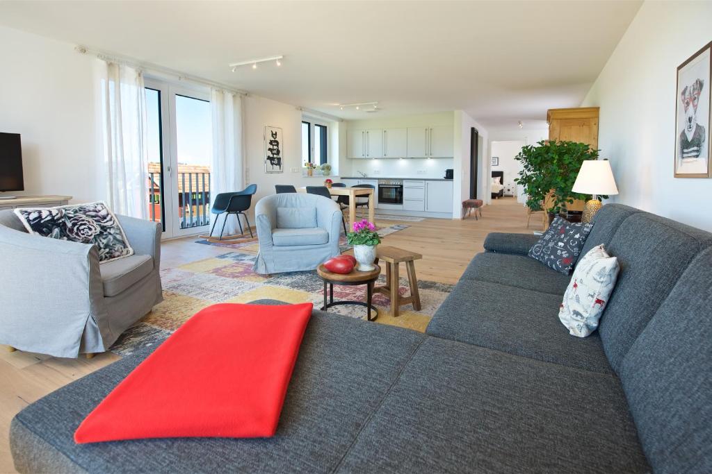 een woonkamer met een blauwe bank en een rode deken bij Herzberger Ferienwohnungen in Scheidegg