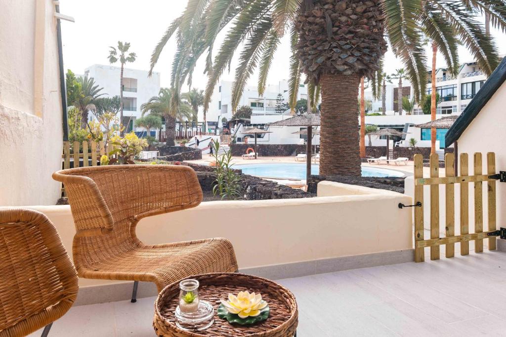 patio z krzesłem i stołem oraz basenem w obiekcie Marisol Apartment Wifi Stunning Pool w Costa Teguise