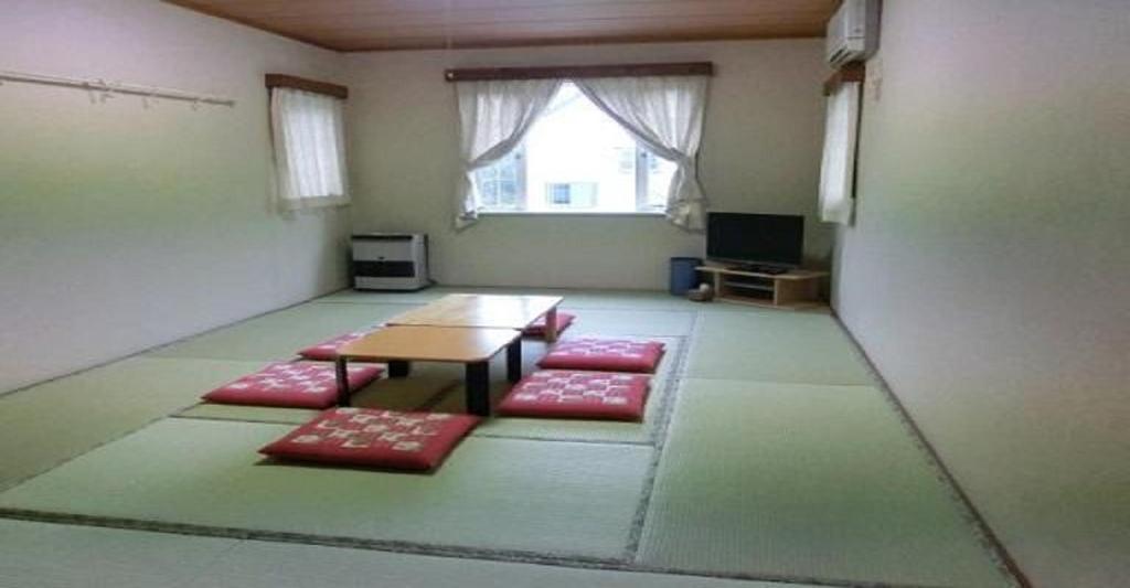um quarto com uma mesa e tapetes vermelhos em Pension Come Relax Tatami-room 12 tatami mats- Vacation STAY 14986 em Minami Uonuma