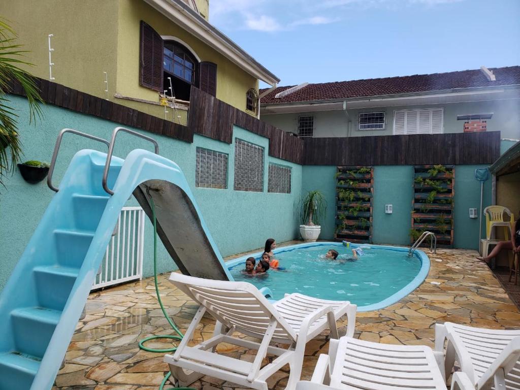 two people in a swimming pool with a slide at Casa em Guaratuba com piscina in Guaratuba