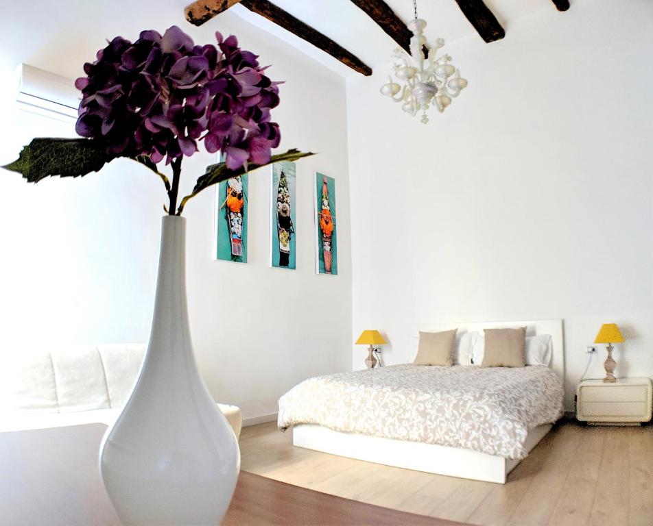 een witte vaas met paarse bloemen in een slaapkamer bij San Carlo Apartment in Napels