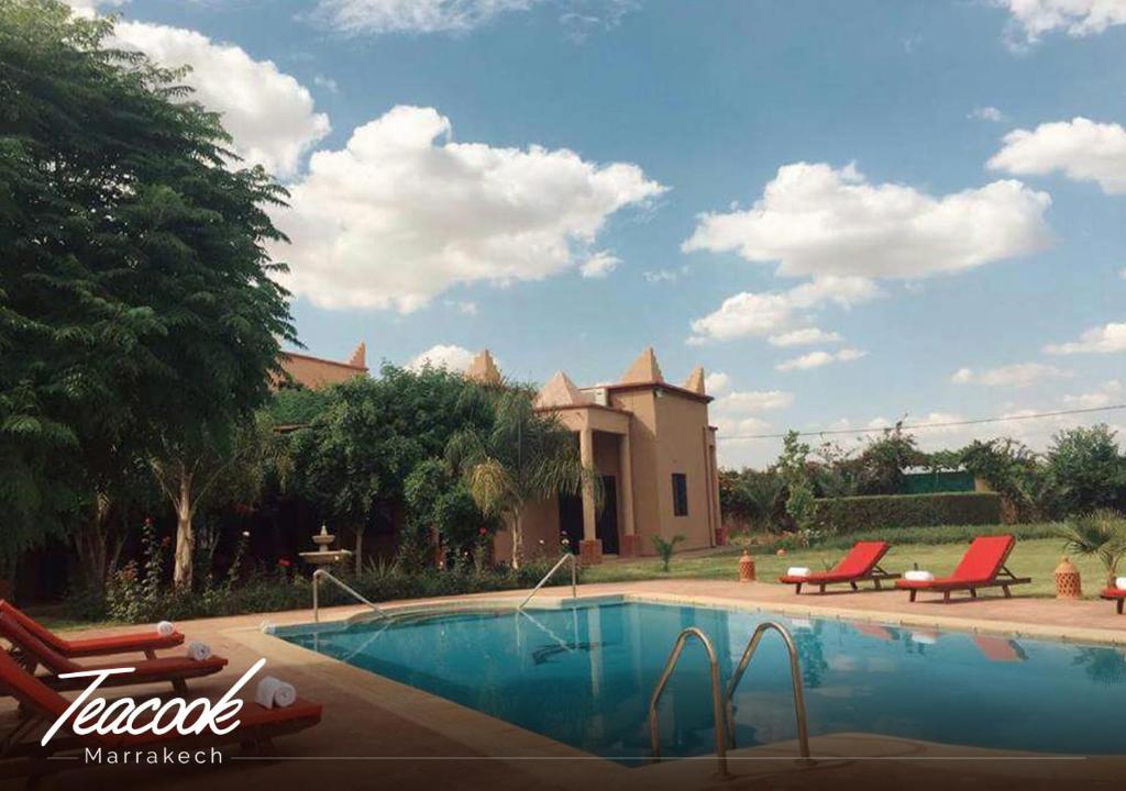 - une piscine avec 2 chaises et une maison dans l'établissement Teacook Marrakech, à Ouled el guerne