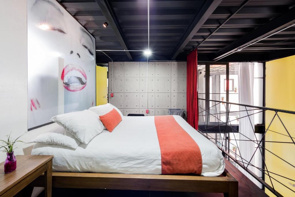1 dormitorio con 1 cama con manta naranja y blanca en Cozy Loft with Balcony, en Ciudad de México